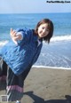 A woman standing on a beach with her arms outstretched.