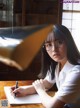 A woman sitting at a table writing in a notebook.