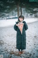 A woman standing in the snow wearing a black coat.