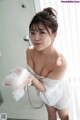 A woman in a white towel is taking a shower.