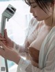 A woman in a white robe is holding a shower head.