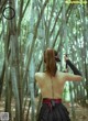 A woman holding a sword in a bamboo forest.