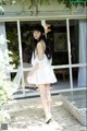 A woman in a white dress standing on a wooden deck.