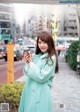 A woman in a green coat standing on a city street.