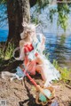 A woman sitting on the ground next to a body of water.