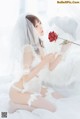 A woman in a white lingerie holding a red rose.