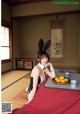 A woman in bunny ears sitting at a table with a plate of fruit.