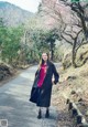 A woman standing on the side of a road next to a tree.