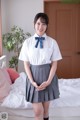 A woman in a school uniform posing on a bed.