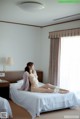 A naked woman sitting on a bed in a hotel room.