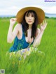 A woman in a straw hat sitting in a field of tall grass.